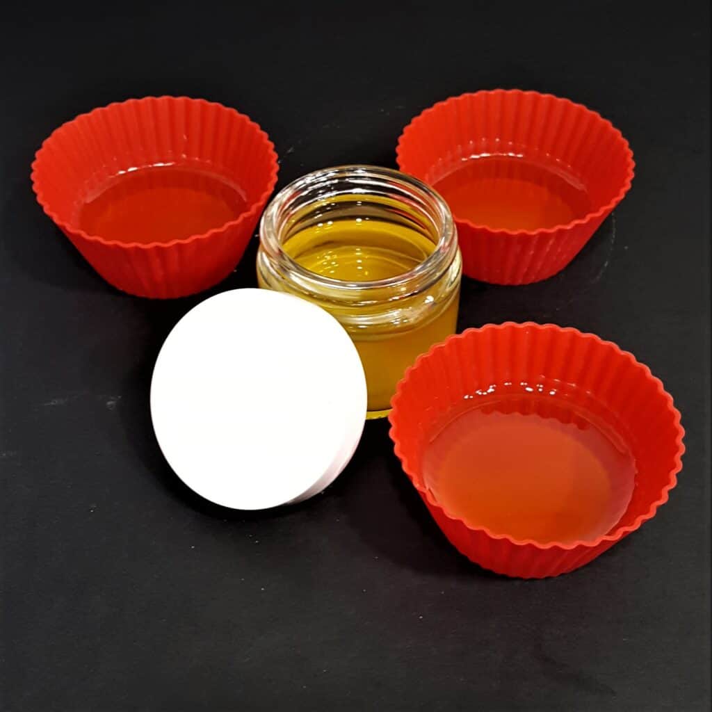 Pour melted beeswax, shea butter and olive oil into containers for the paw balm.