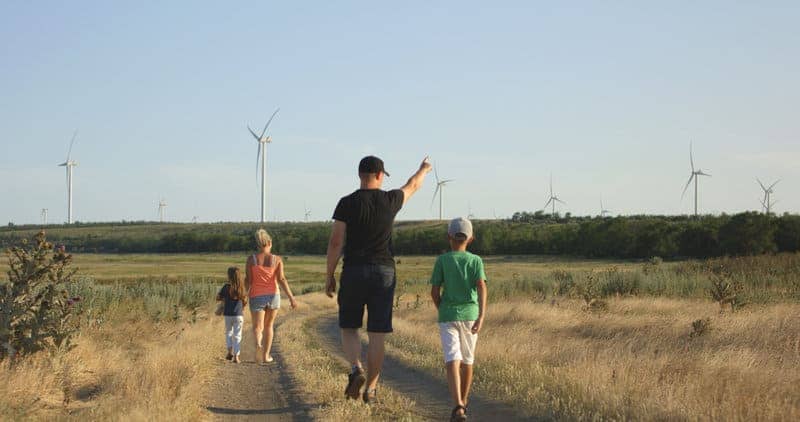 Family walking and looking at wind turbines - sustainability for kids